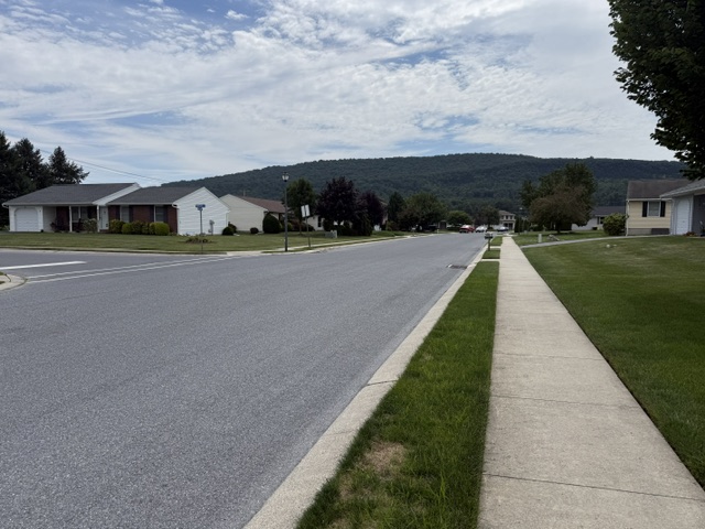 Sidewalk and residential street in Newburg Village with hillside views in Newmanstown PA.