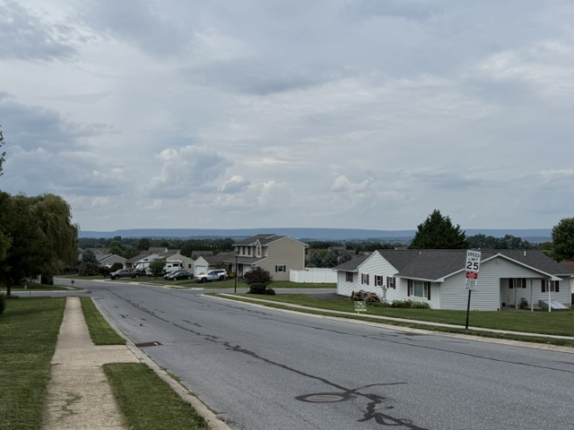 Residential street in Newburg Village Newmanstown PA with homes and distant hillside views.