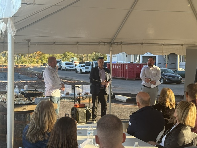 Three project representatives speaking during the Scottish Hollow development tour with new construction in the background.